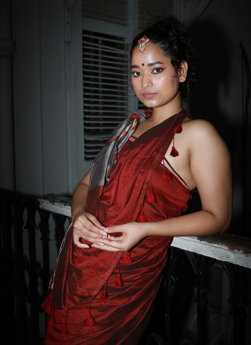 Woman in a red saree standing indoors with a dark background