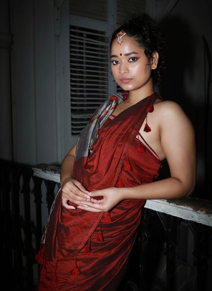 Woman in a red saree standing indoors with a dark background