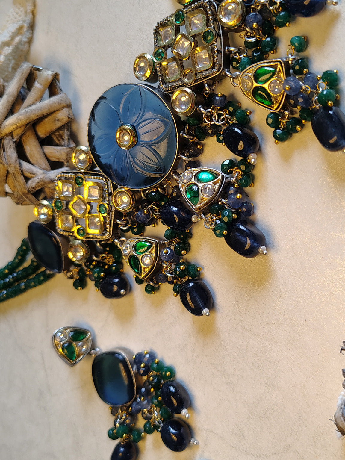 Close-up of a necklace with green and blue beads on a textured surface
