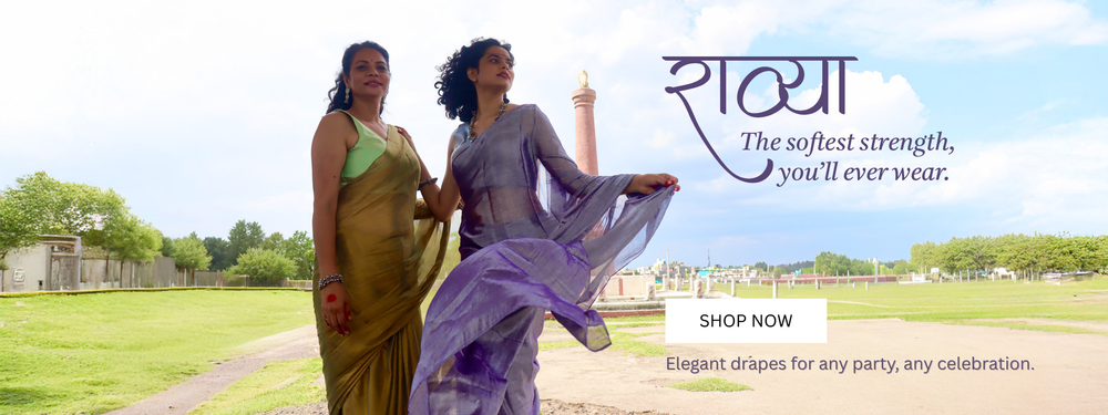 Two women in handloom golden saree and purple saree standing outdoors with shop now button